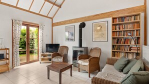 A cozy living room with a fireplace, a television, a bookshelf, and a dining area. - Nice Holiday Home by the sea (De Haan)