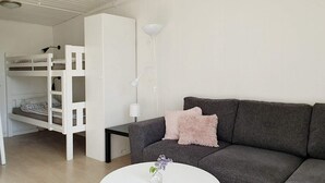 A modern living room with a grey sofa, a white coffee table, and a bunk bed in the background. - 4 Star Holiday Home in Karlskrona (Karlskrona)
