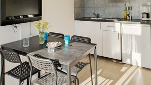 A compact kitchen with a dining area, a flat-screen TV, and a microwave. - 4 Star Holiday Home in Karlskrona (Karlskrona)