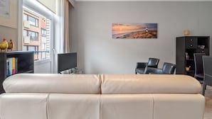 A modern living room with a leather sofa, a flat-screen TV, and a bookshelf. - Ideal Holiday Home With Garage (Blankenberge)