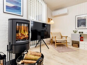 Ein Wohnzimmer mit Kamin, Fernseher, Sessel und Bücherregal.