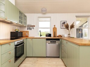 A kitchen with green cabinets, a wooden countertop, a dishwasher, and a window with a view. - 4 Star Holiday Home in Lokken (Lokken)