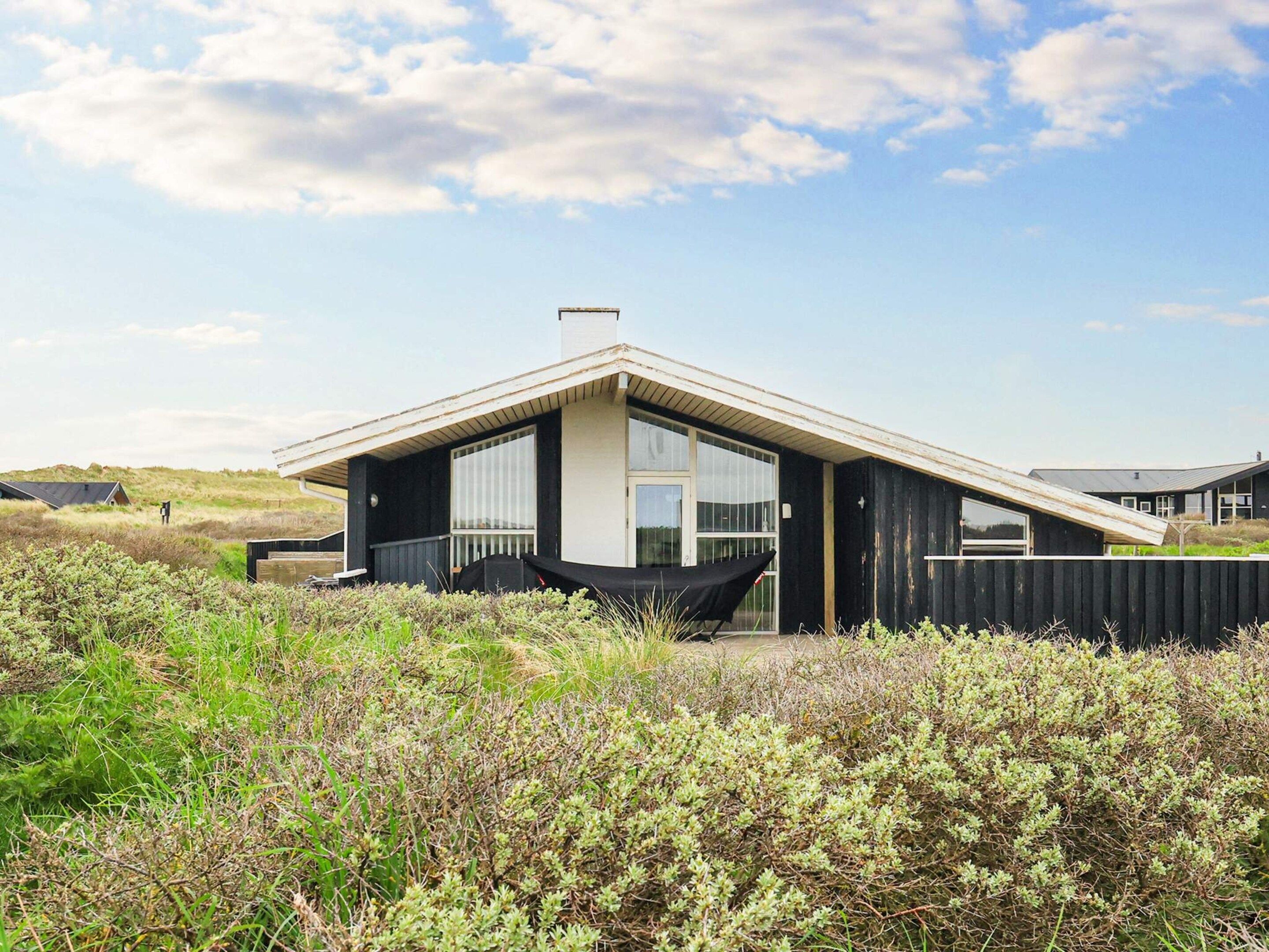 A modern house with a sloped roof, large windows, and a black exterior.