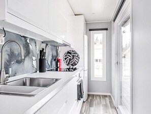 A modern kitchen with a stainless steel sink, a built-in oven, and a window with a view of the outside. - 6 Person Holiday Home in Virserum (Virserum)