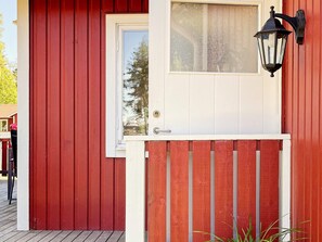 A red wooden door with a white window and a black wall-mounted light fixture.