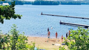 A lake with a dock extending into the water, surrounded by trees and a sandy beach. - 6 Person Holiday Home in Virserum (Virserum)