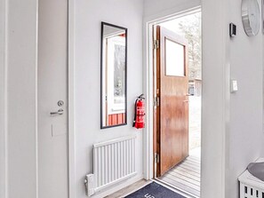 A door with a wooden panel, a white radiator below, a black doormat, and a red fire extinguisher on the wall.