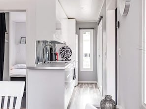 A modern kitchen with a stainless steel sink, a kettle, and a decorative plate. - 6 Person Holiday Home in Virserum (Virserum)