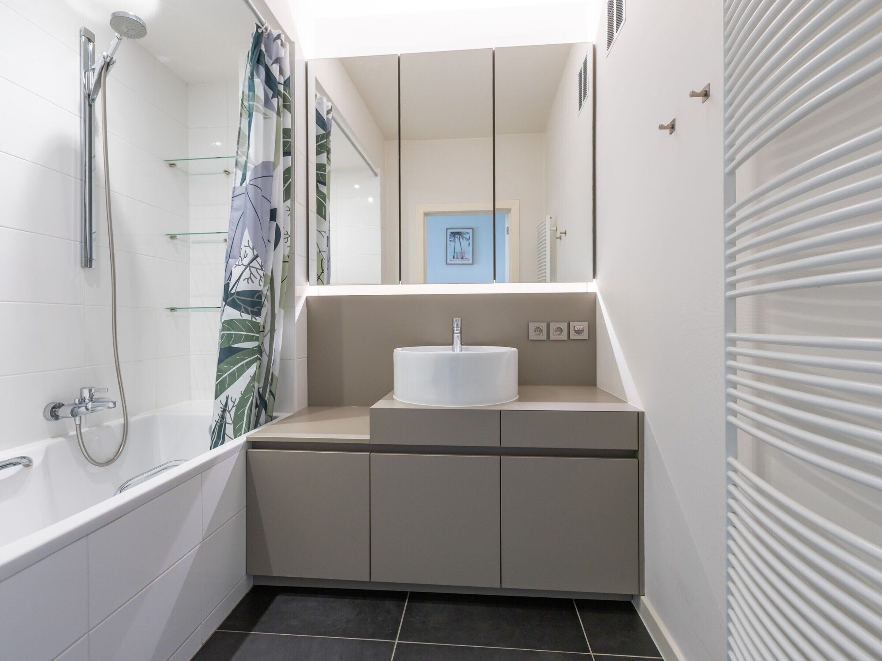 A modern bathroom with a bathtub, shower, and a sink with a mirror above.