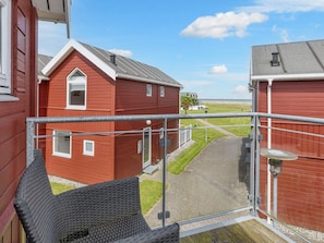 En rød bygning med balkon, der udover en belagt plads og en græsplæne.