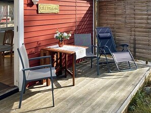 A wooden deck with a table and two chairs, a small potted plant, and a sign reading 'Lillstugan'. - 4 Star Holiday Home in Ljustero (Ljusterö)