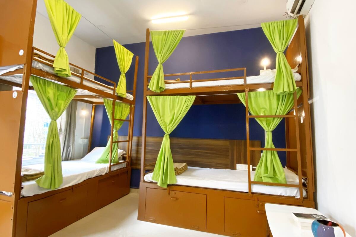 A room with bunk beds, a desk, and an air conditioning unit.