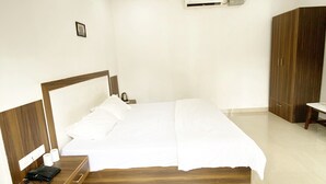 Een slaapkamer met een houten bed, nachtkastje met telefoon, plafondventilator en een airconditioning.