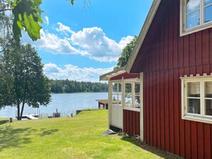 Una casa de madera roja con puerta y ventanas de vidrio que dan a un lago.