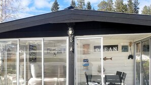A covered outdoor seating area with glass walls, a sign reading "LIFE'S AN OCEAN," and a wooden deck. - 4 Star Holiday Home in Lulea (Luleå)