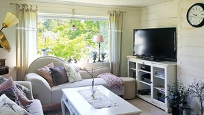 A living room with a sofa, a coffee table, a television on a cabinet, and a clock on the wall. - 4 Star Holiday Home in Myggenas (Myggenäs)