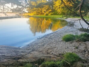 A calm lake with a wooden dock extending into the water, surrounded by trees and grassy areas. - 4 Star Holiday Home in Myggenas (Myggenäs)
