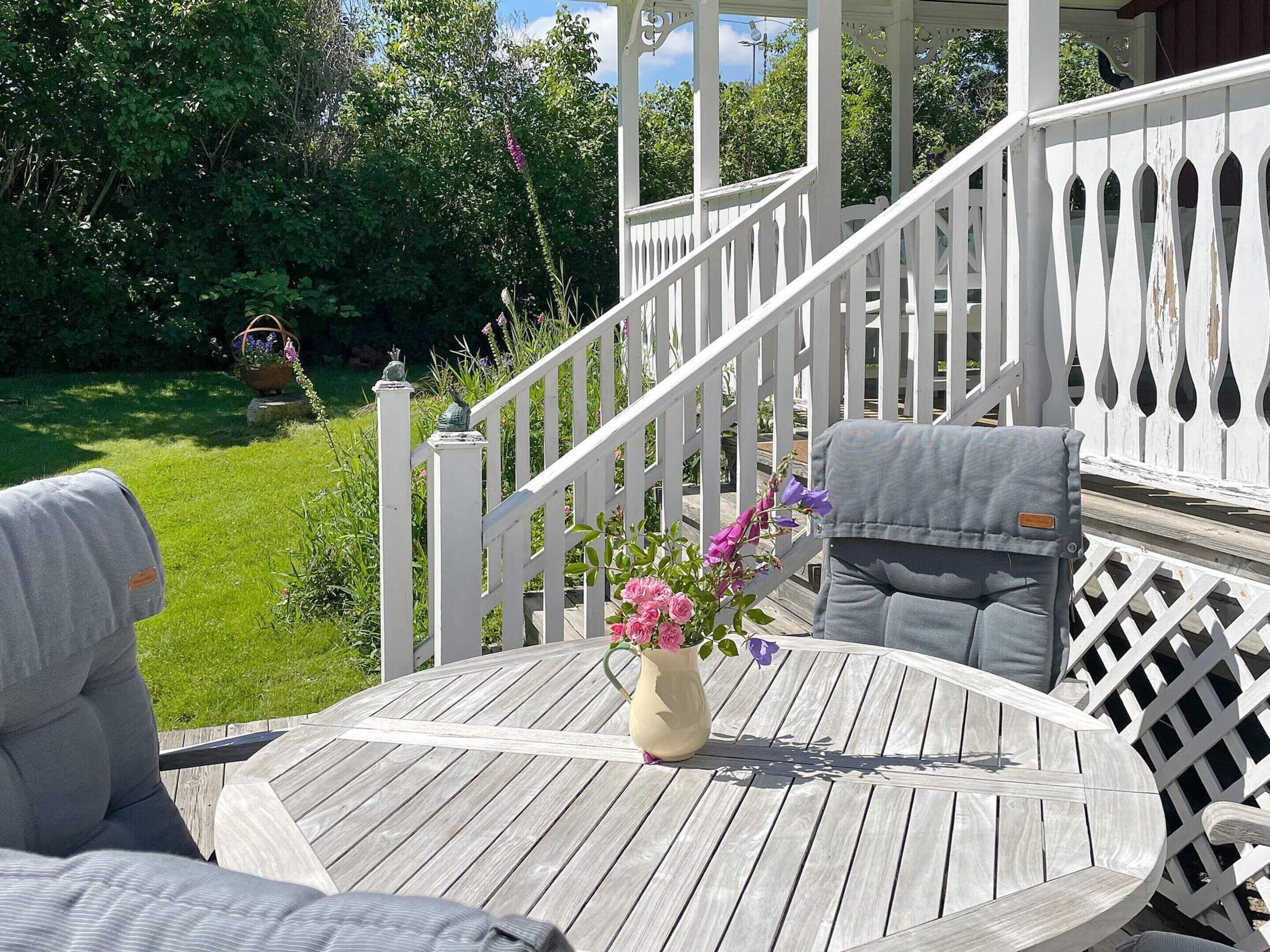 A wooden deck with a white railing, a round table, and two chairs.