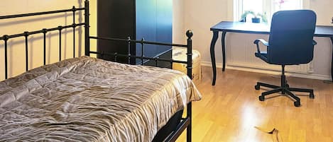 Une chambre à coucher avec un lit, un bureau, une chaise, une horloge et une fenêtre.