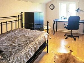 Une chambre à coucher avec un lit, un bureau, une chaise, une horloge et une fenêtre.