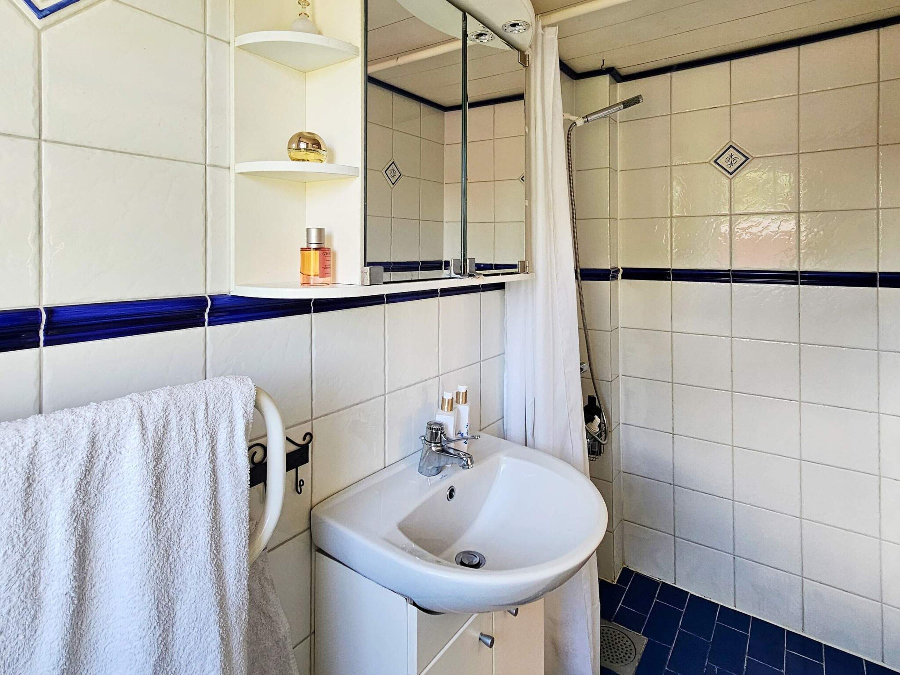 A bathroom with a white sink, a mirror, and a shower.