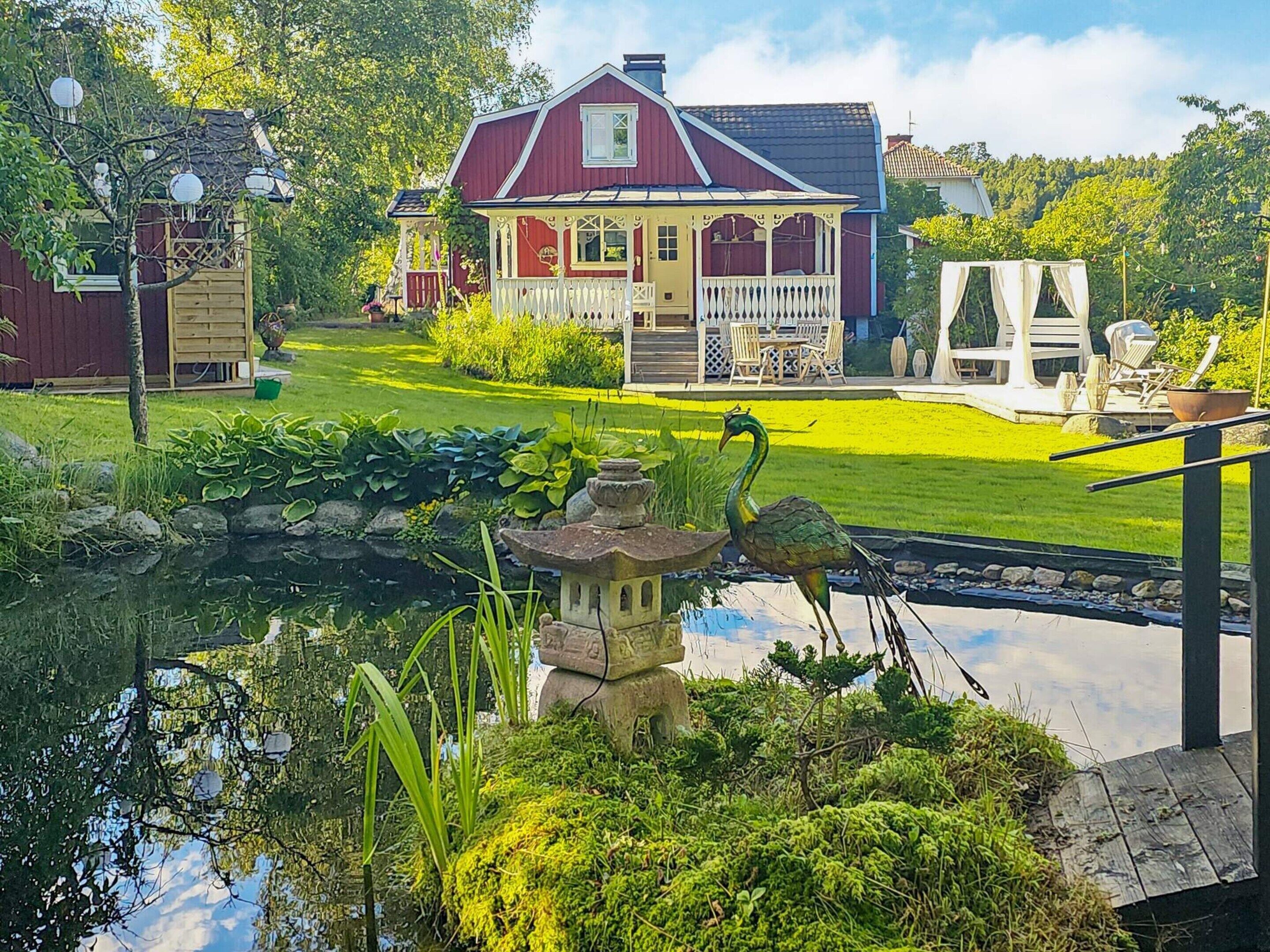 Una casa con giardino, uno stagno e mobili da esterno.