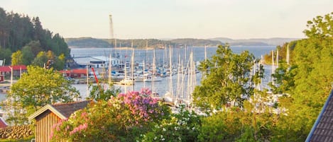 A marina with boats docked, surrounded by greenery and a small building.