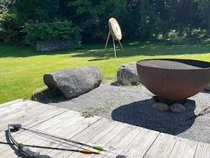 A wooden deck with a grill, a fire pit, and a target in a garden setting. - 4 Star Holiday Home in Myggenas (Myggenäs)