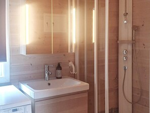 A bathroom with a wooden vanity, a white sink, a mirror, and a shower enclosure. - 5 Person Holiday Home in Treungen (Nissedal)