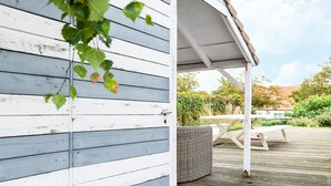 A white wooden building with a covered porch and a picnic table. - Holiday Home Nieuwpoort Near Sandy Beach (Nieuwpoort)