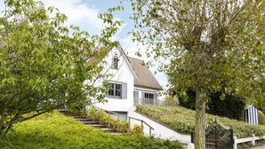 A white house with a red-tiled roof, a white picket fence, and a paved pathway leading to the entrance. - Holiday Home Nieuwpoort Near Sandy Beach (Nieuwpoort)