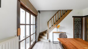 A spacious room with a large window, a wooden staircase, and a wooden table. - Holiday Home Nieuwpoort Near Sandy Beach (Nieuwpoort)