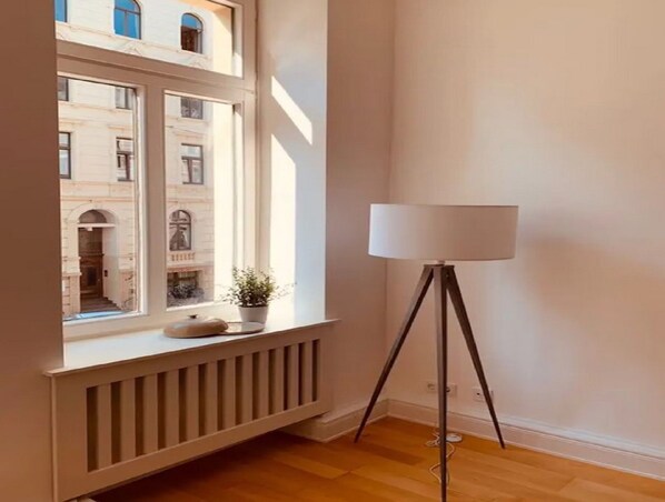 A room with a large window, a radiator, a floor lamp, and a potted plant on the windowsill. - Inviting Holiday Home With Balcony or Terrace (Straubing)