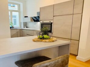 A modern kitchen with a white countertop, a built-in oven, and a small dining area with a bench. - Inviting Holiday Home With Balcony or Terrace (Straubing)