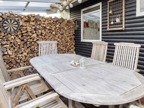 A wooden table with chairs, a dartboard, and a lantern in a rustic outdoor setting. - 5 Person Holiday Home in Roslev (Roslev)