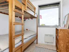 A bunk bed room with a window, a radiator, and a small desk with a picture frame. - 5 Person Holiday Home in Roslev (Roslev)