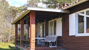 A wooden house with a porch, a table, and a bench. - 5 Person Holiday Home in Falkenberg (Falkenberg)