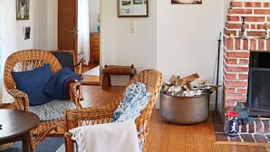 A cozy living room with wicker furniture, a fireplace, and a wooden floor. - 5 Person Holiday Home in Falkenberg (Falkenberg)