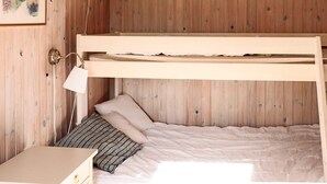 Ein Etagenbett mit Kopfteil, ein Nachttisch, eine Lampe und ein gerahmtes Bild an der Wand.