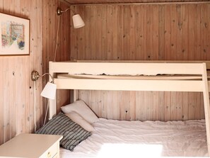Un lit superposé avec une tête de lit, une table de chevet, une lampe et un tableau encadré au mur.