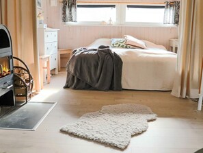 Ein Schlafzimmer mit einem Bett, einem Kamin, einem Schminktisch und einem Fenster mit Vorhängen.