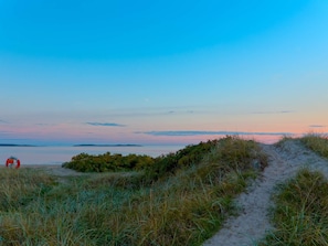 Un sentier menant à la plage et à la mer, avec une bouée de sauvetage visible.