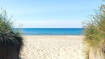 A sandy beach with a clear view of the ocean.
