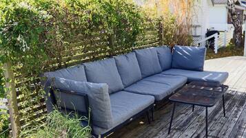 A wooden deck with a gray sofa and a small table.