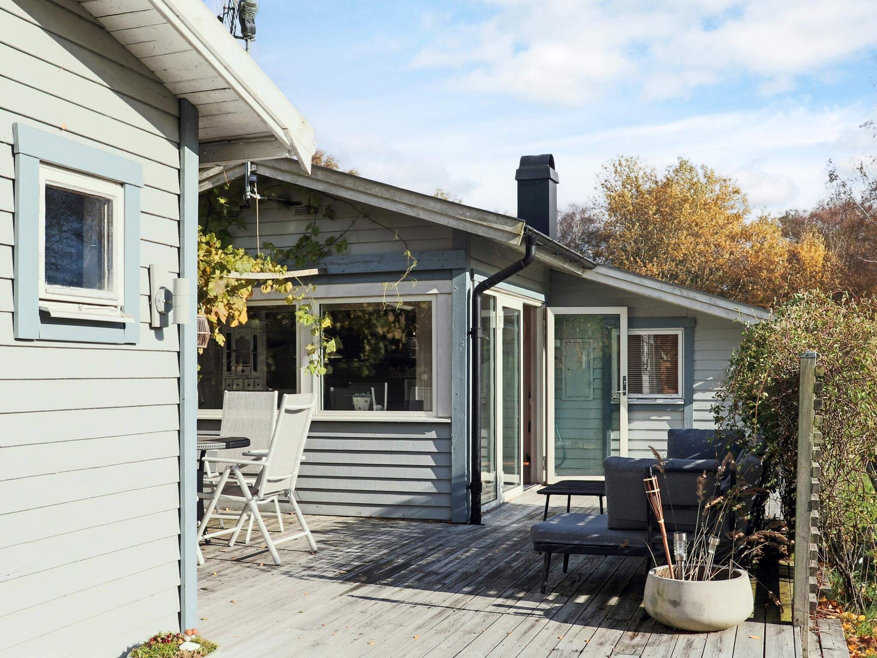 Een huis met een overdekte veranda, buitenmeubels en een schoorsteen.