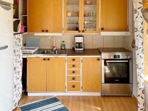 A compact kitchen with wooden cabinets, a stainless steel sink, a Bosch oven, and a coffee maker. - 4 Person Holiday Home in Holmsjo (Holmsjö)