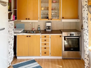 A compact kitchen with wooden cabinets, a stainless steel sink, a Bosch oven, and a coffee maker. - 4 Person Holiday Home in Holmsjo (Holmsjö)