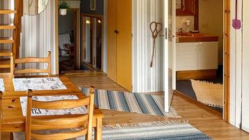A wooden dining table with chairs, a striped rug, and a kitchen area with a sink and cabinets.