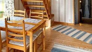 Une table de salle à manger en bois, des chaises, un escalier et un tapis à rayures.