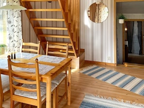 A wooden dining table with chairs, a staircase, and a striped rug. - 4 Person Holiday Home in Holmsjo (Holmsjö)